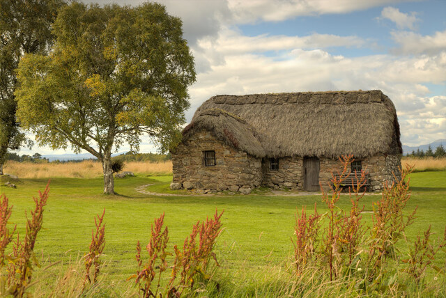 Old Leanach Cottage framed by lush greenery, offering a tranquil connection to Scotland’s past.