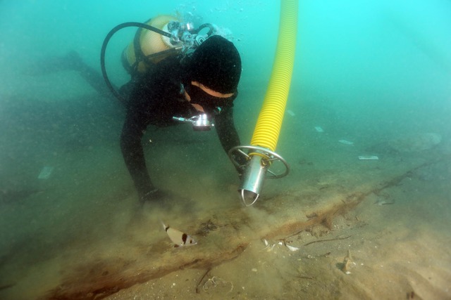 Workers onboard carefully secure the recovered pieces of the shipwreck to transport them to restoration facilities.