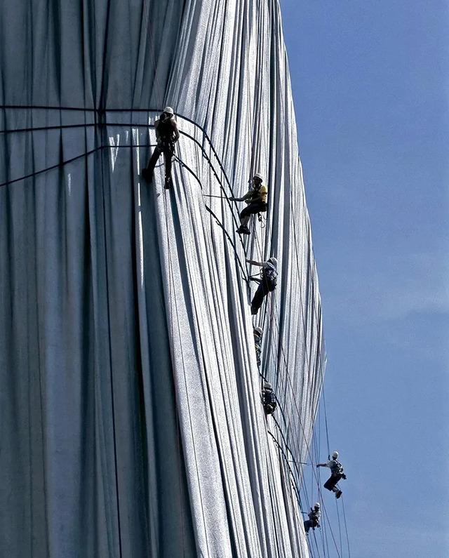 Rope specialists working at height ensure the fabric remains securely in place over the historic structure.