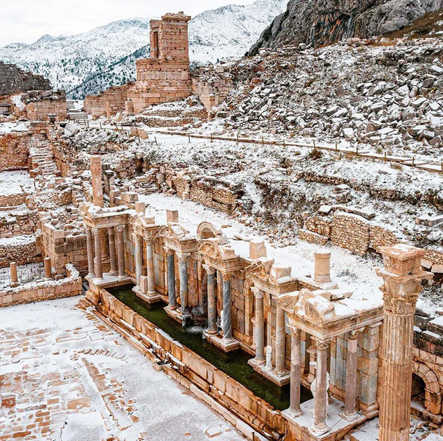 The Ancient City of Sagalassos covered in a blanket of snow, showcasing the Nymphaeum’s grandeur in a serene winter setting.