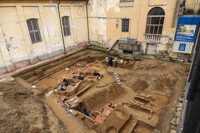 The archaeological team meticulously working on uncovering the ancient tomb structures at the cloister site in Pavia.