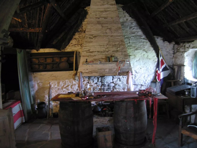 The cozy interior of Old Leanach Cottage with its central hearth, a glimpse into its historical significance.