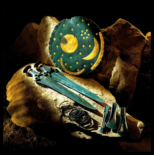 The enigmatic Nebra Sky Disk, surrounded by other Bronze Age artifacts discovered alongside it, sparking debates about its origins and purpose.