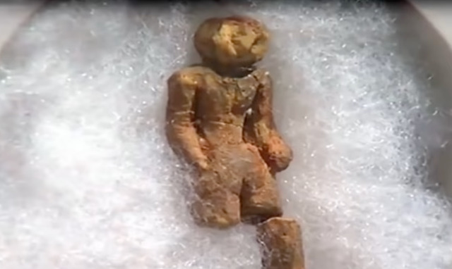 The figurine's distinct facial and body features preserved in clay, suggesting a sophisticated artistic technique.