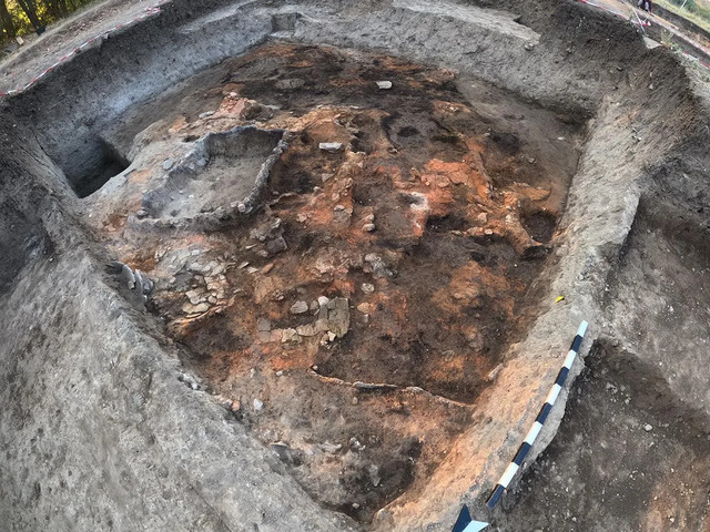 The long, rectangular burnt house reveals built installations for food storage alongside numerous in-situ storage vessels, painting a vivid picture of ancient domestic life.