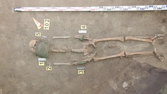 The remains of a woman adorned with bronze neck rings and arm rings, offering a glimpse into ancient burial traditions.