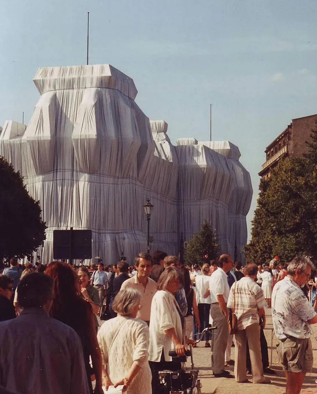 Visitors walk near the south side of the Wrapped Reichstag, showcasing the monumental scale of the silvery fabric installation.