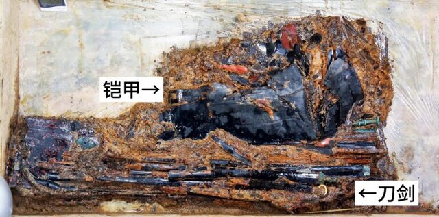 The soil block containing fish-scale armor and weaponry as it was excavated from the tomb of the Marquis of Haihun. Labels indicate key artifacts, including the armor (鎧甲) and swords (刀劍). (Credit: Jiangxi Provincial Institute of Cultural Relics and Archaeology)