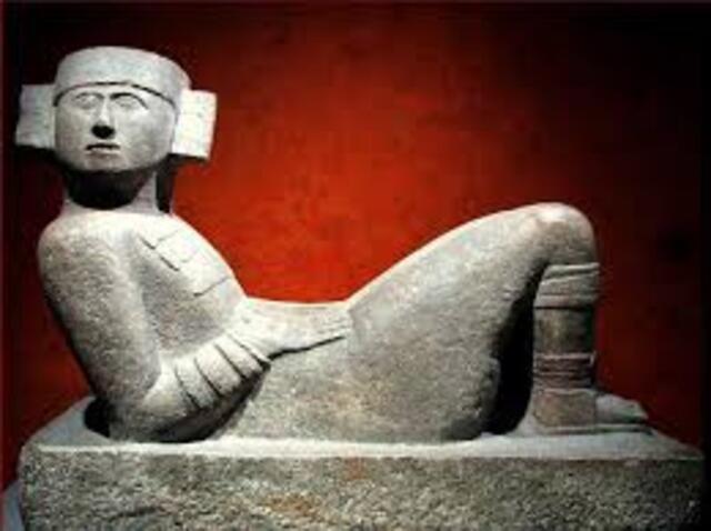 This photo highlights a Chac Mool sculpture displayed in a museum setting, emphasizing the intricate details of its carving and the cultural significance it held for the Maya and Toltec civilizations.