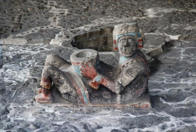 This rare depiction showcases a Chac Mool statue that still retains remnants of its original paint, providing valuable insights into the vibrant aesthetics of Mesoamerican art and its connection to deities like Tlaloc.