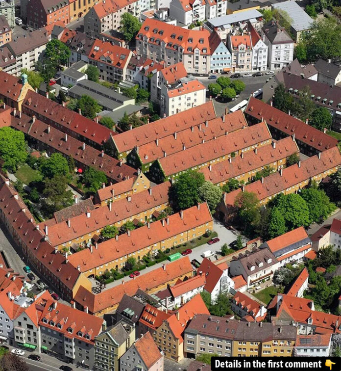 An aerial shot capturing the historical Fuggerei complex, showcasing its distinctive red-roofed architecture nestled within Augsburg, Germany.