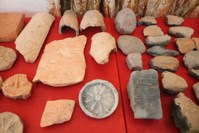 A collection of artifacts uncovered from the Luy Lau ancient citadel, including terracotta fragments, stone tools, and decorative items, showcasing the diversity of materials used in ancient Vietnamese craftsmanship.