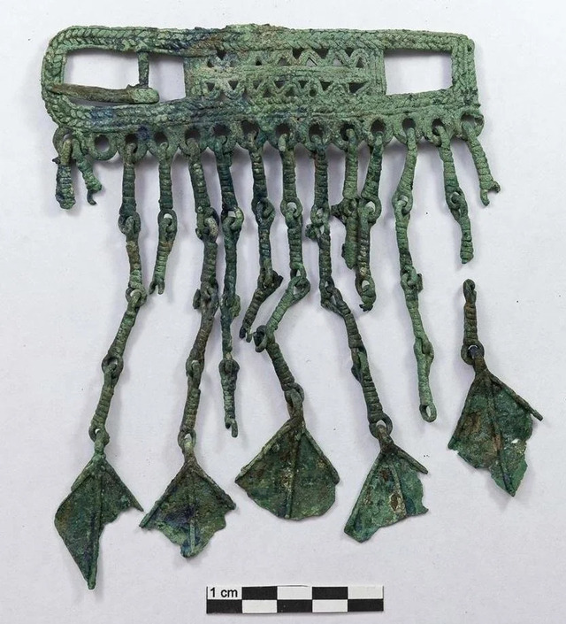 A complex artifact featuring interwoven patterns and dangling chains, likely part of an ornate belt or high-status decorative item. (Credit: Institute of Archaeology of the Russian Academy of Sciences)