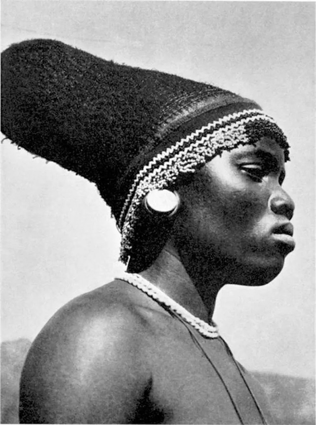 A Mangbetu woman in profile, her elongated head and ornate hairstyle symbolizing power, intelligence, and aesthetic ideals in her community.