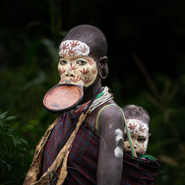 A Suri mother and baby from Ethiopia display traditional lip plates and intricate face painting, reflecting the vibrant culture of their tribe. (Credit: Jayne Mclean)