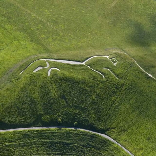 A breathtaking aerial view of the Uffington White Horse, Britain's oldest chalk hill figure, etched into the rolling Oxfordshire landscape.