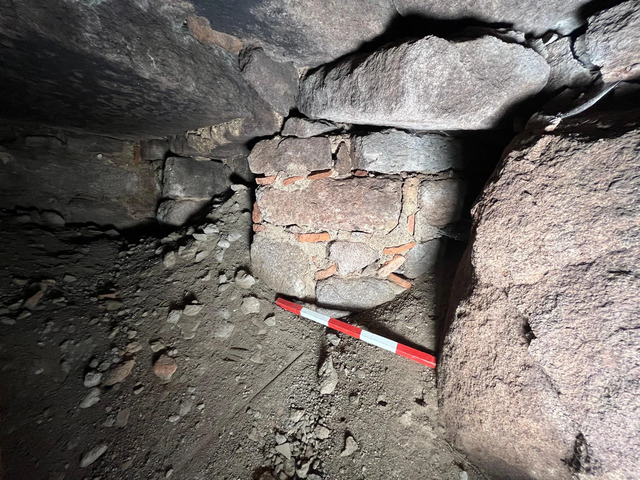 A close-up of the structural remains within the bath, highlighting the brick and stone masonry of the 14th century.