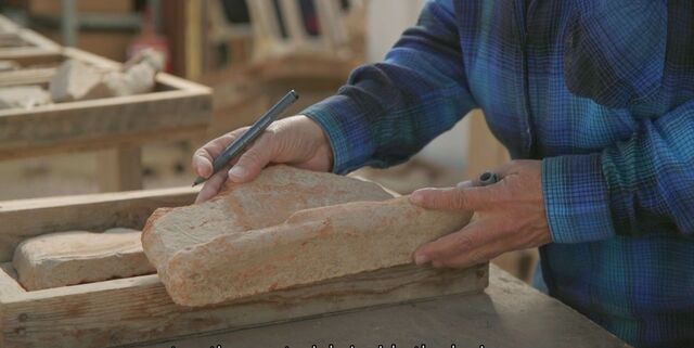 A conservator meticulously documenting an inscribed Roman roof tile, highlighting the craftsmanship and precision of Roman military construction techniques.