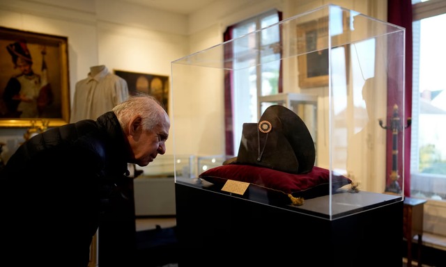 A museum visitor admires one of Napoleon’s signature wide-brimmed black hats, a symbol of his authority during his reign over 19th-century France. (Photograph: Christophe Ena/AP)