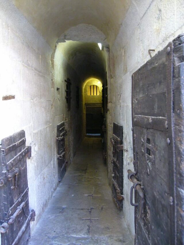 A narrow corridor inside the New Prisons of the Doge’s Palace, with heavy wooden doors guarding the cells.