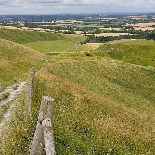 A panoramic view from White Horse Hill, with the figure visible against the scenic backdrop of the Vale of White Horse.