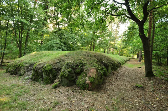 A side view of a megalithic mound near Dolice, revealing its elongated triangular shape and structural design.