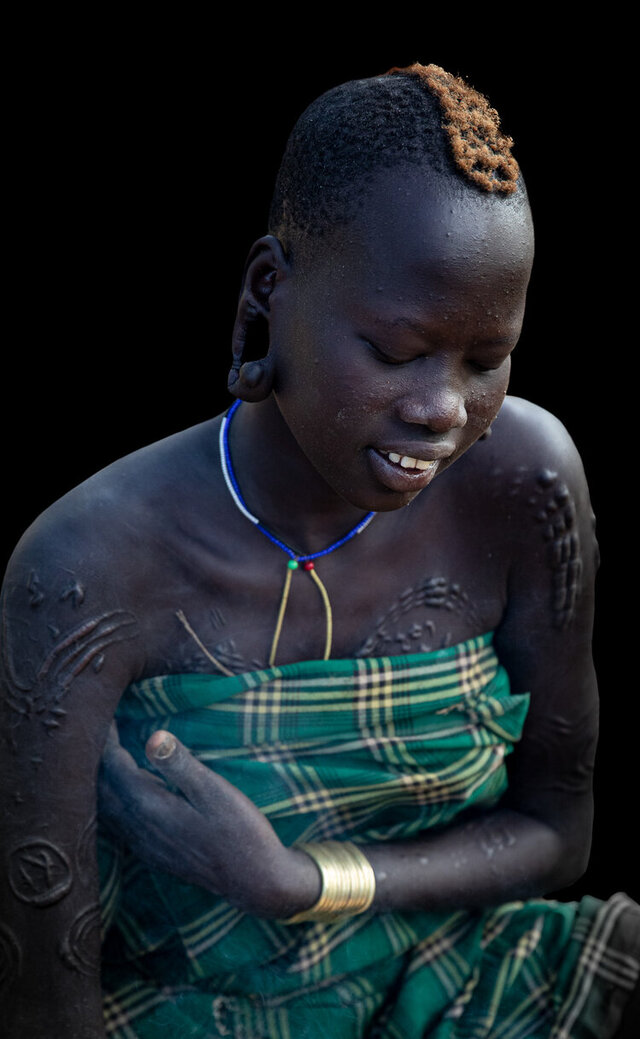 A young woman from the Suri tribe proudly displaying intricate body scarifications, a mark of beauty and cultural identity in her community. (Credit: Jayne Mclean) 