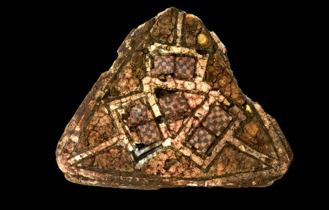 Among the grave goods, a triangular brooch with glass mosaic and gold enamel, likely from Ireland or England, was discovered in a rock crevice. Though the grave had been disturbed, remnants of its treasures were found nearby.