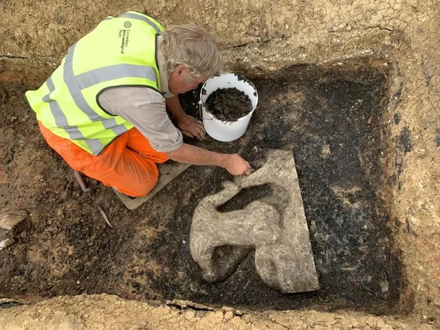 Archaeologist carefully excavating the Triton statue from a disused clay-lined water tank, revealing its preserved state after nearly 2,000 years.