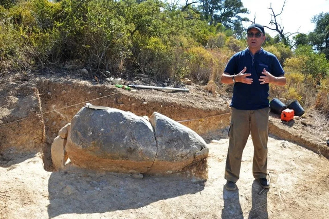 Archaeologist discussing the historical context of the menhir with the press on-site.