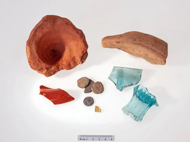 Artifacts discovered at the site, including Roman pottery fragments, a gold fragment, and a silver denarius from Julius Caesar’s era. Credit: ADA Zug / Res Eichenberger.