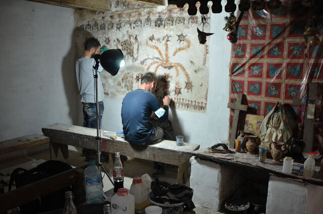 Conservators are restoring a stunning mural of flowering plants in the Ramírez family home in Chajul. Beside the artwork stands an altar adorned with a cross and symbols of Catholic devotion.