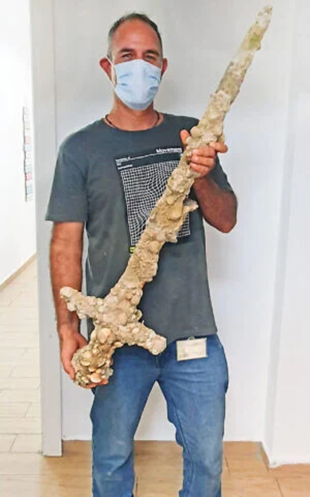 Diver Shlomi Katzin proudly displays the Crusader sword he unearthed off Neve Yam's coast in October 2021. (Credit: Nir Distelfeld/Israel Antiquities Authority)