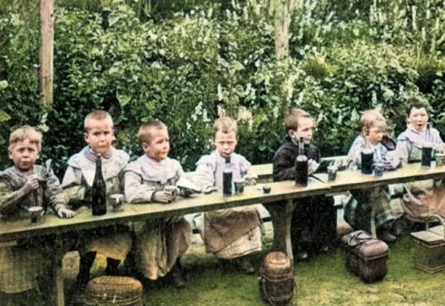 French schoolchildren enjoying their midday meal with wine on the table, showcasing a cultural norm of the early 20th century.