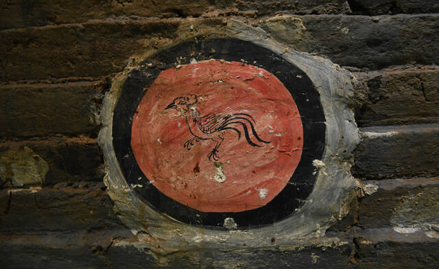 On the roof of one tomb, a star symbolizes the heavens, while the eastern wall features a red disc with a bird—likely a phoenix or crow—representing the sun