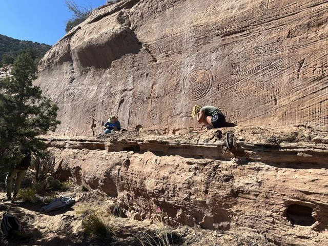 Researchers work on a rugged cliffside to document and study spiral petroglyphs and other significant markings on a sandstone wall. Credit: Jagiellonian University.