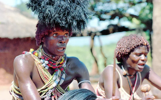 Sangomas photographed during a shamanic healer graduation 40 years ago. The man wears an ochre-colored wig beneath his feathers, and the woman has ochre worked into her hair. Both appear to be in a trance state. (Photo: Bob Forrester)