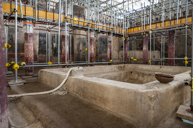 The central bath in the peristyle, surrounded by scaffolding during excavation, highlighting the architectural grandeur of the cold room in the villa's thermal spa. (Credit: MIC-Parco Archeologico di Pompei)