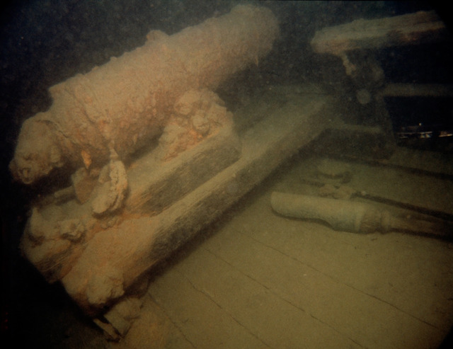 This 1982 photograph of the armed schooner Hamilton showcases artifacts from the War of 1812, including a carronade—a short-barreled, cast-iron cannon—and a gunpowder ladle still visible on the deck nearly 170 years after the ship sank.