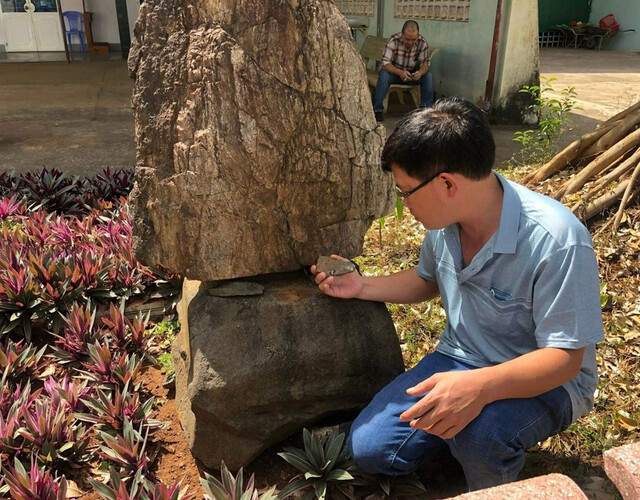 The author standing beside a stone block originally from the An Phu Cham ruins, now found at Phu Tho Church. (Photo: X.H.)