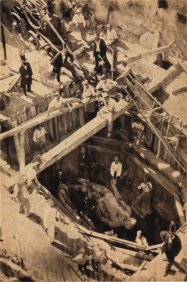 The dramatic excavation site in 1864 reveals the colossal Hercules Mastai Righetti statue lying amidst ancient ruins under Palazzo Pio Righetti.