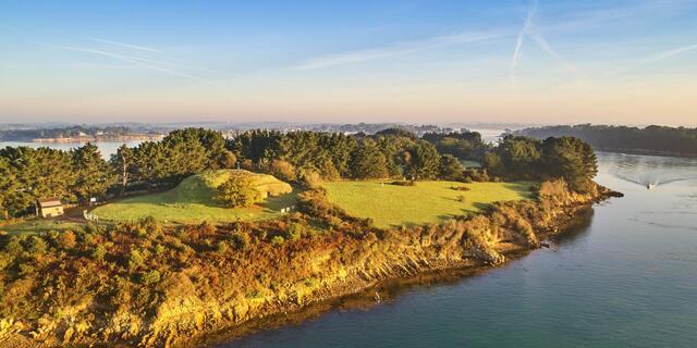 The island of Gavrinis, with its prominent passage tomb mound, rises majestically over the water. (Credit: Brittany Tourism)