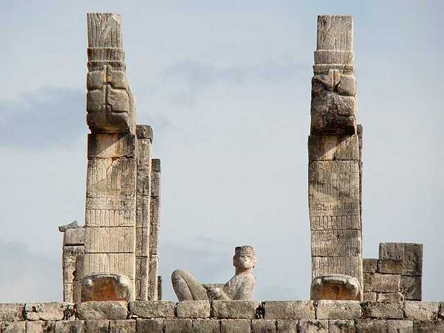 This image captures the imposing presence of a Chac Mool statue overlooking the ceremonial architecture, emphasizing its role as a mediator between the spiritual and physical realms.