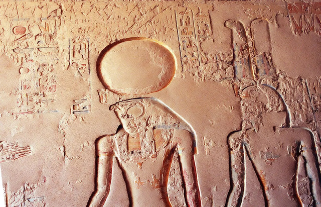 Within the Tomb of Ramesses IV (1153–1147 B.C.), behold the falcon-headed Ra, crowned by a solar disc, standing alongside Amun, depicted with his distinctive double-plume headdress.