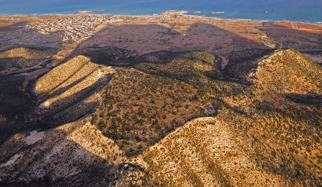 An aerial view of the ancient city of Ptolemais in Libya, revealing the sprawling remains of the once-thriving urban center. This vantage point highlights the city's strategic coastal location, which contributed to its significance during the Hellenistic and Roman periods.